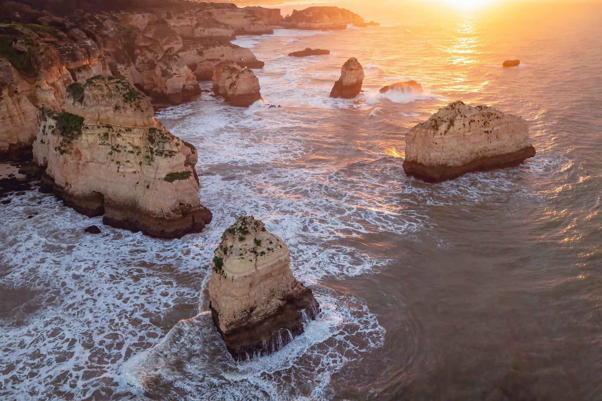 An aerial view of a cliff overlooking the ocean at sunset.