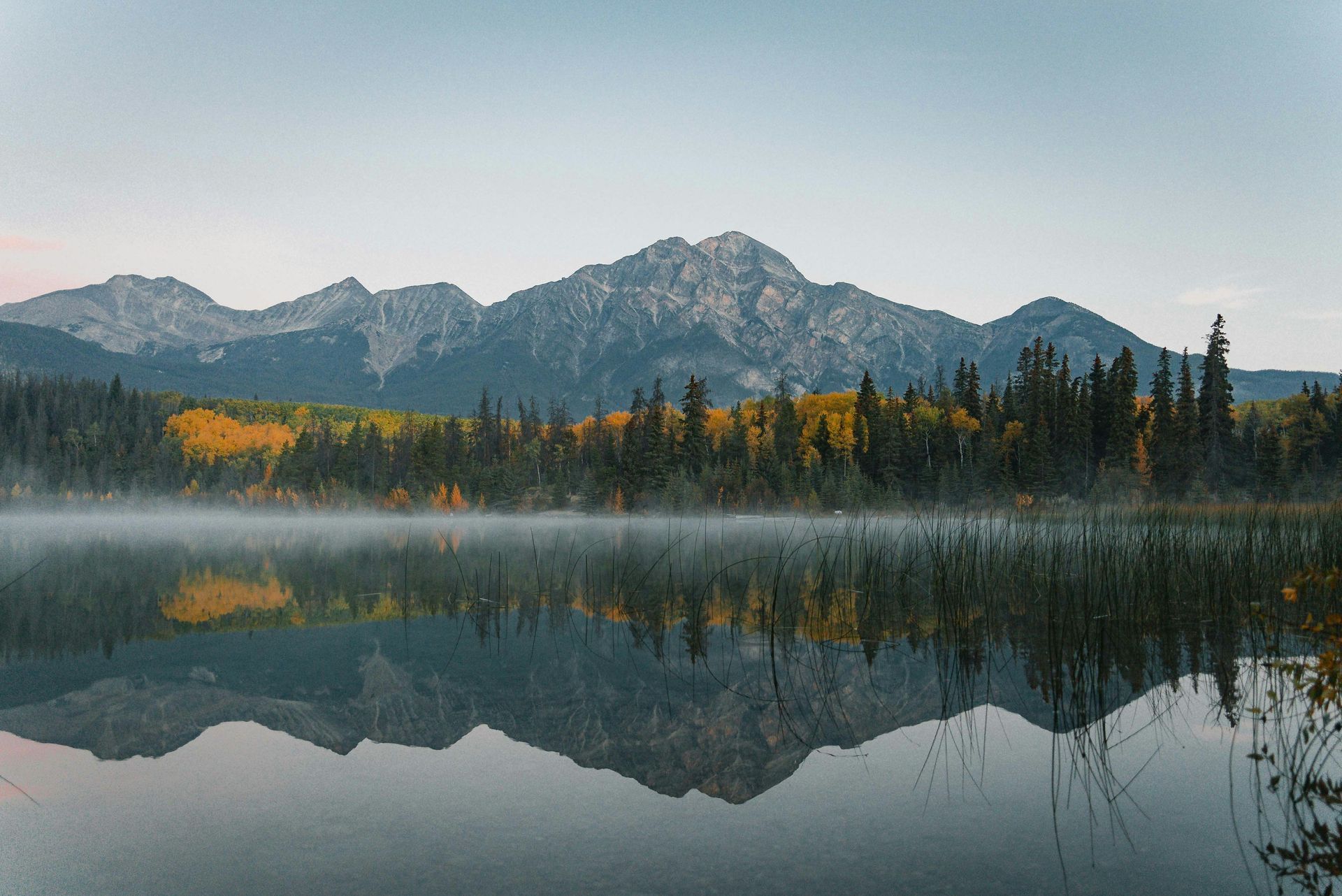 A lake with mountains in the background and trees on the shore.