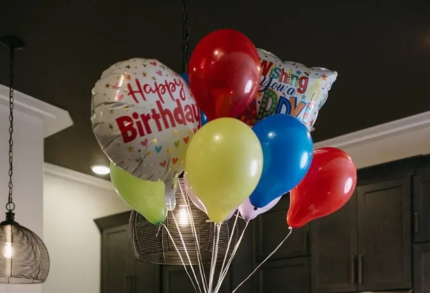 A bunch of birthday balloons are sitting on a table.