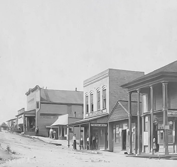 A black and white photo of a row of buildings in a small town.