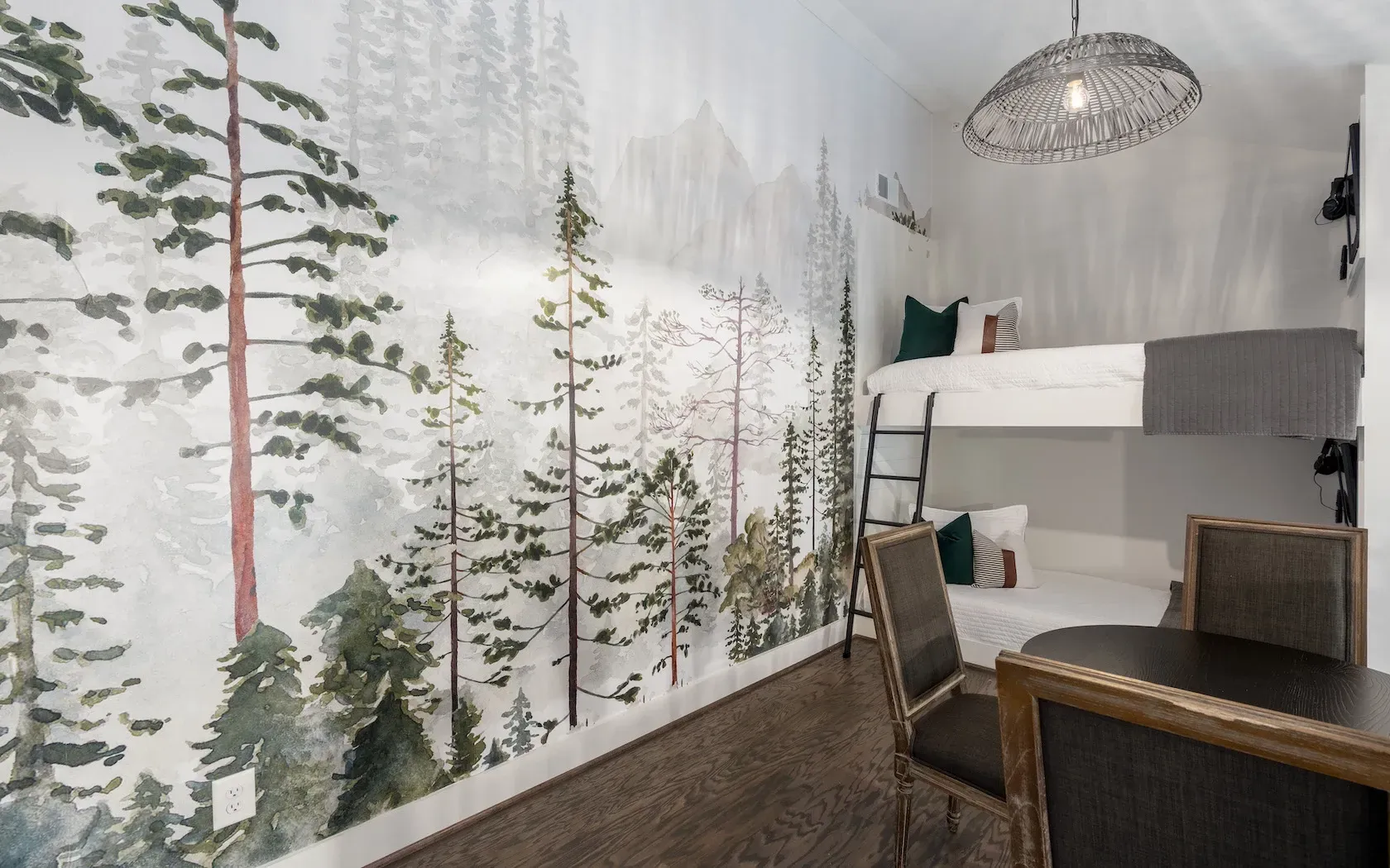 A bedroom with a bunk bed and a painting of trees on the wall.