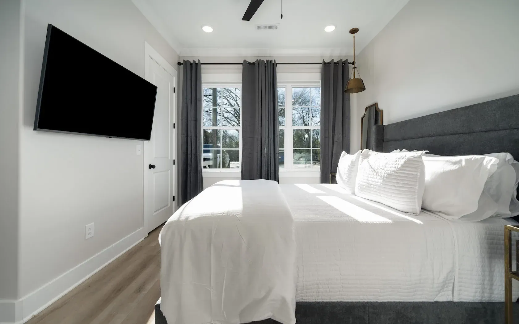 A bedroom with a large bed and a flat screen tv on the wall.