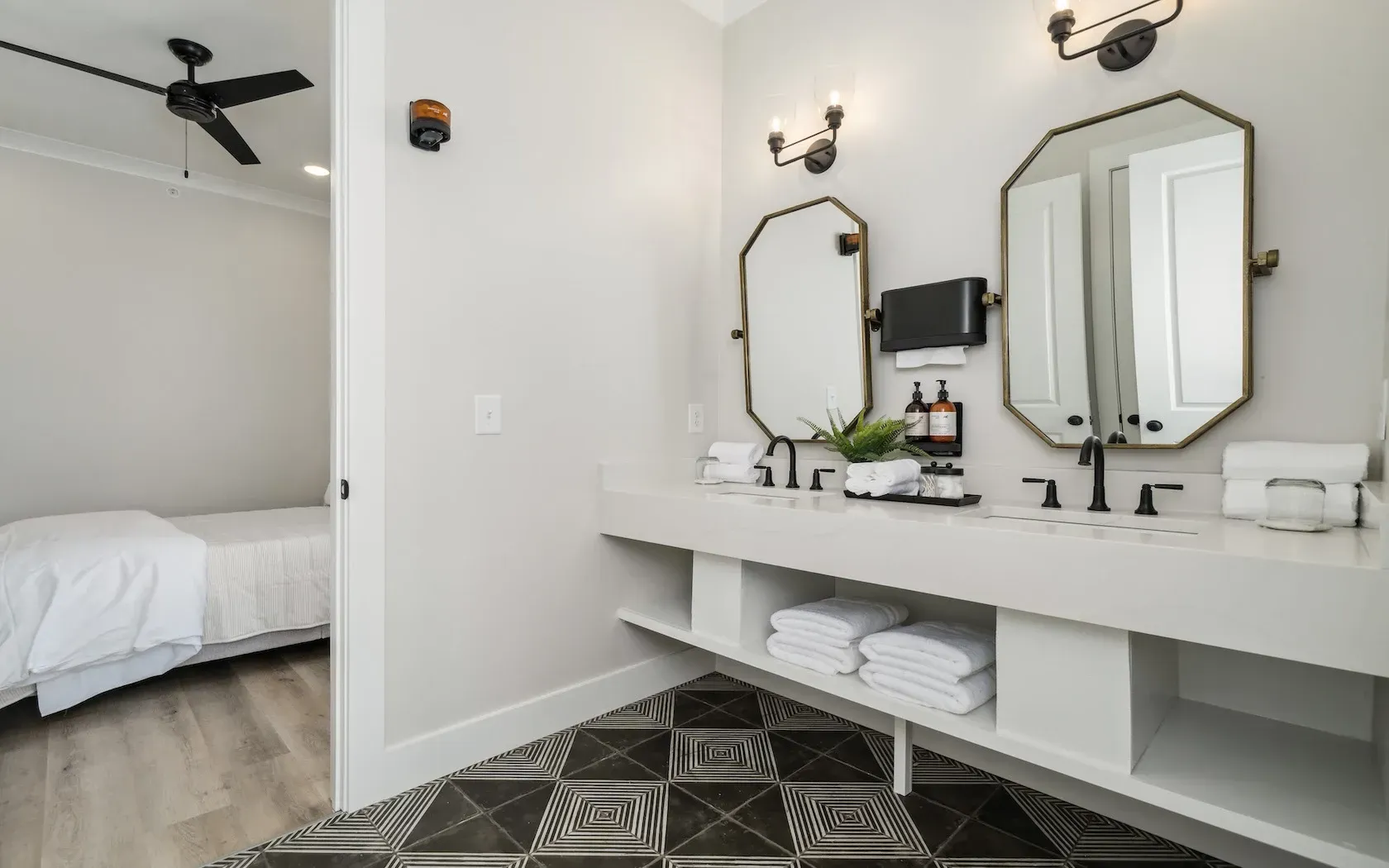 A bathroom with two sinks , two mirrors and a ceiling fan.