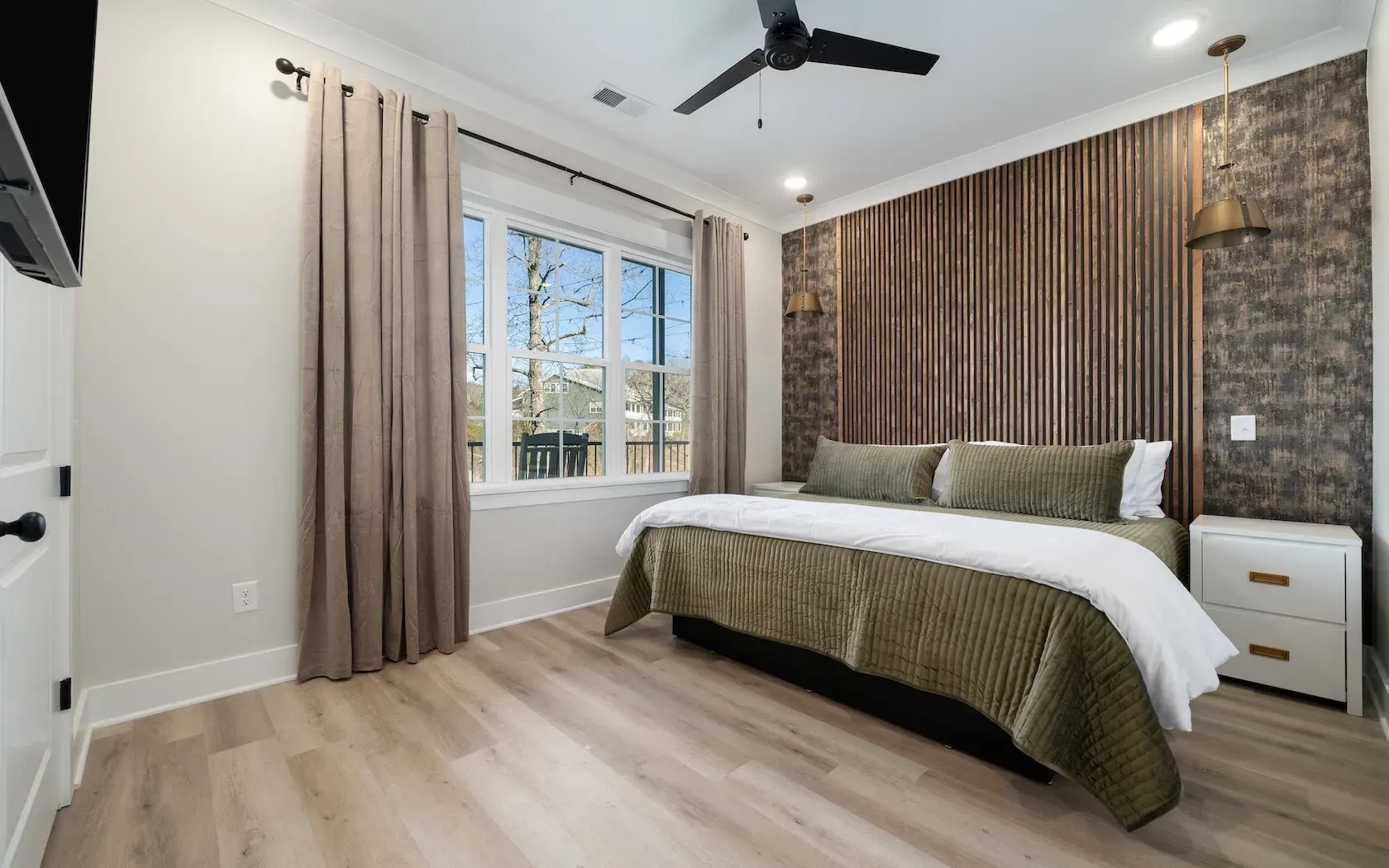 A bedroom with a large bed and a ceiling fan.