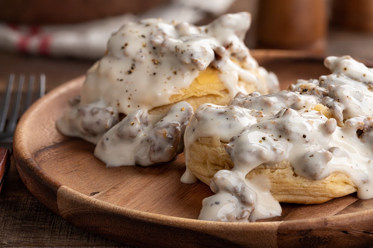 Two biscuits with gravy on a white plate.