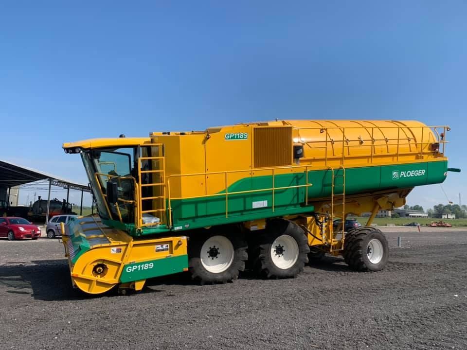 Una mietitrebbia gialla e verde è parcheggiata in un parcheggio.