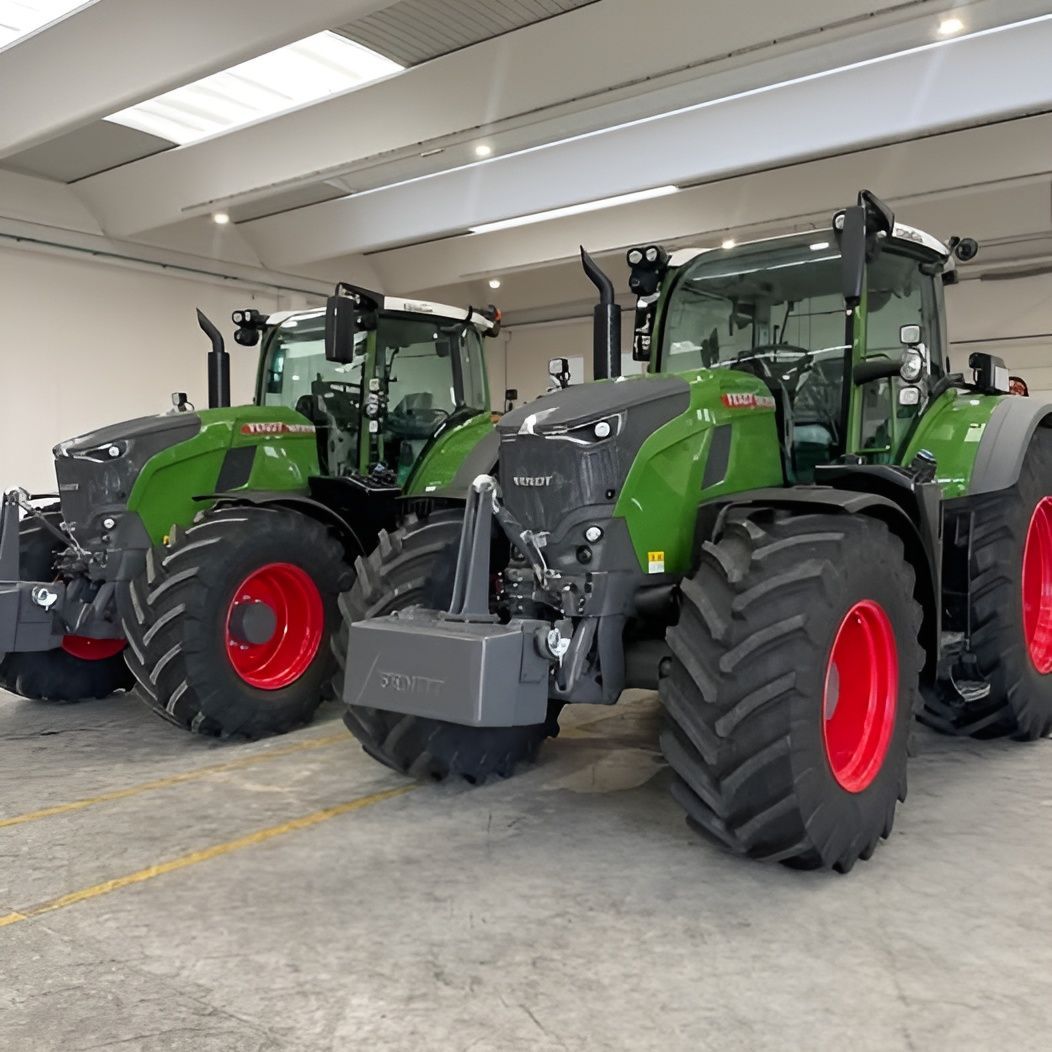 Due trattori verdi con pneumatici rossi sono parcheggiati uno accanto all'altro in un garage.