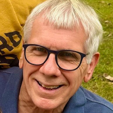 A close up of a man wearing glasses and smiling.