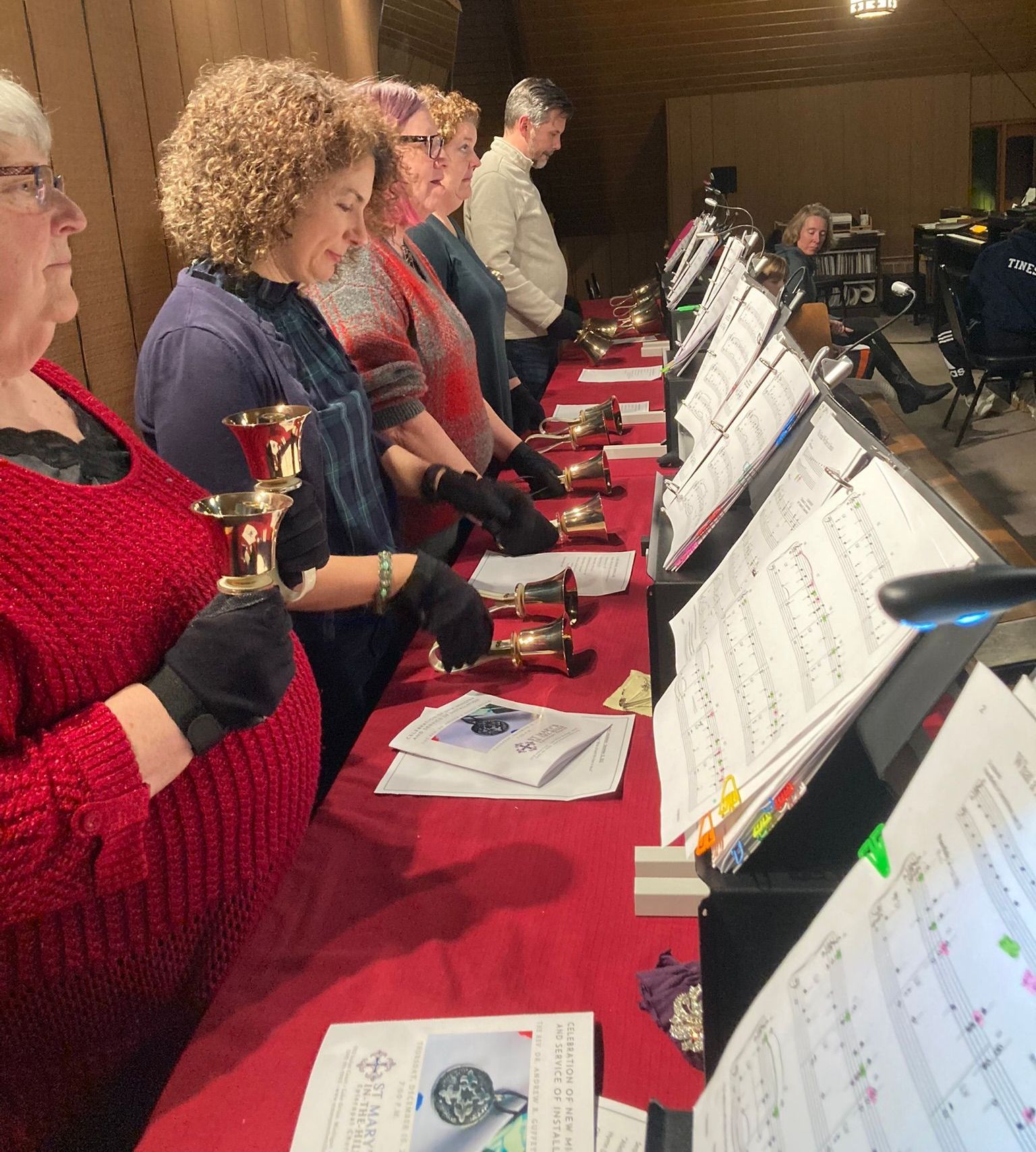 A woman in a red sweater is holding a bell