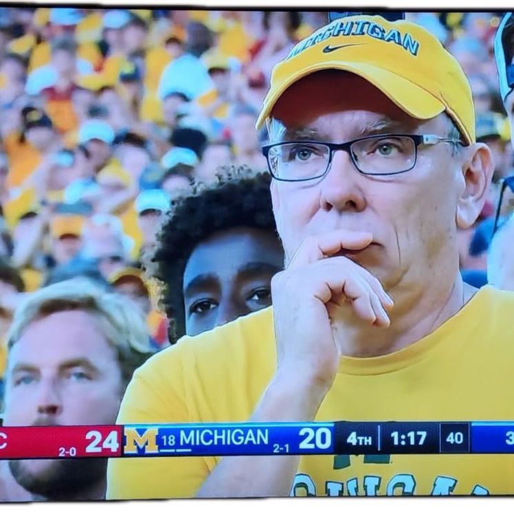 A man wearing a yellow hat with michigan on it