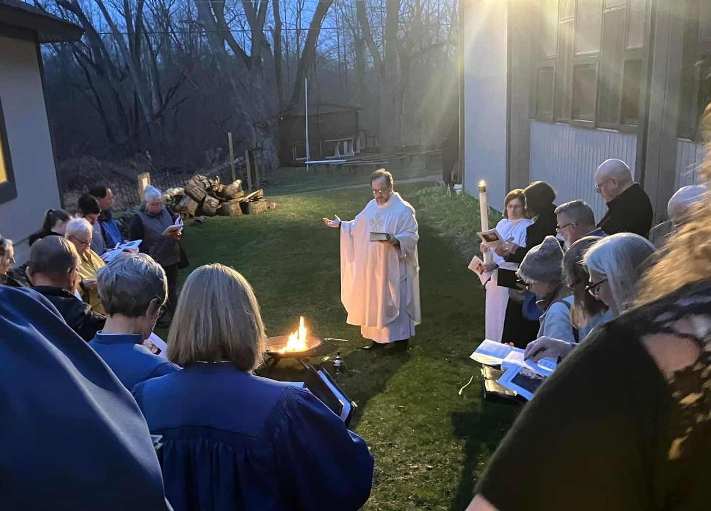 A man in a white robe stands in front of a group of people