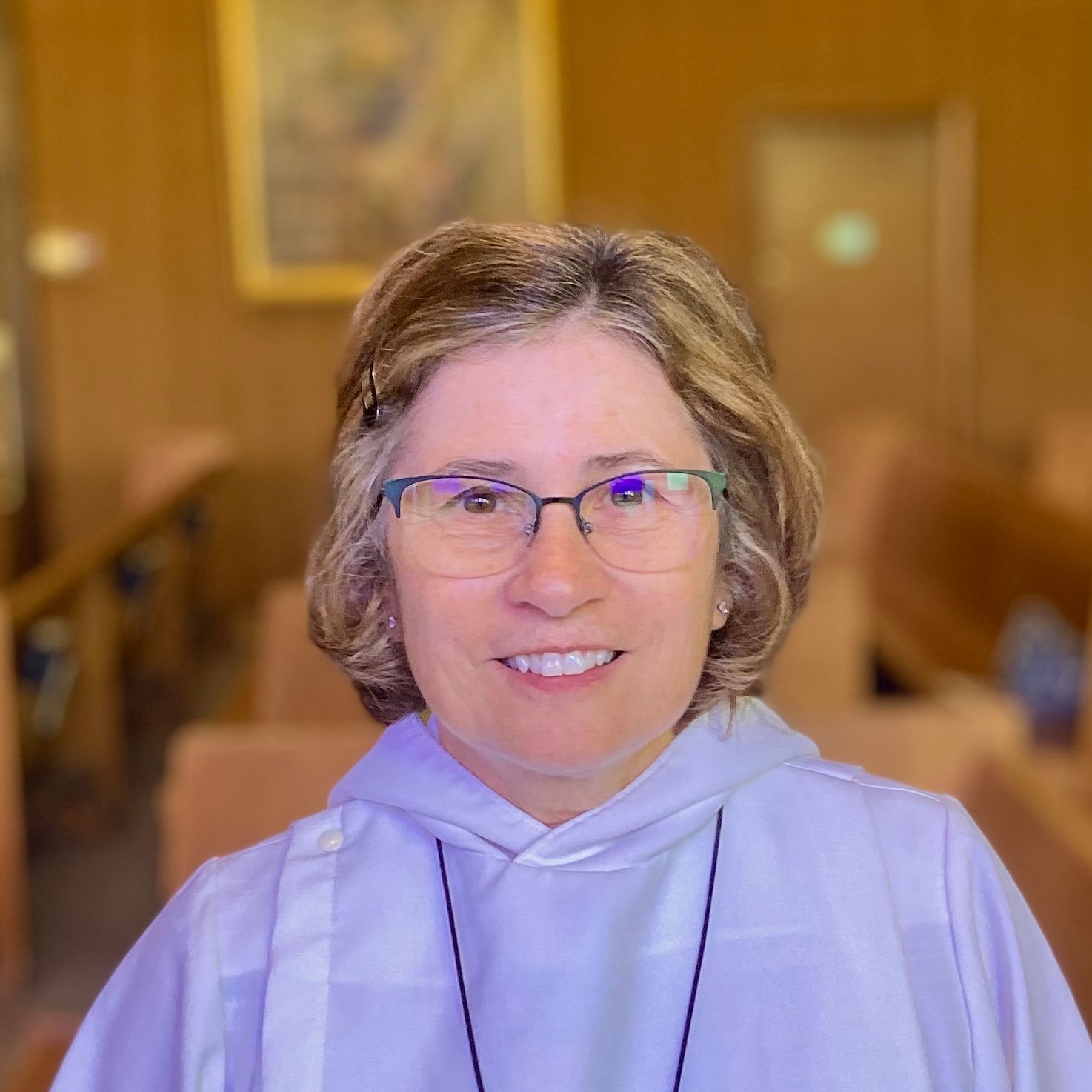 A woman wearing glasses and a white robe is smiling for the camera.