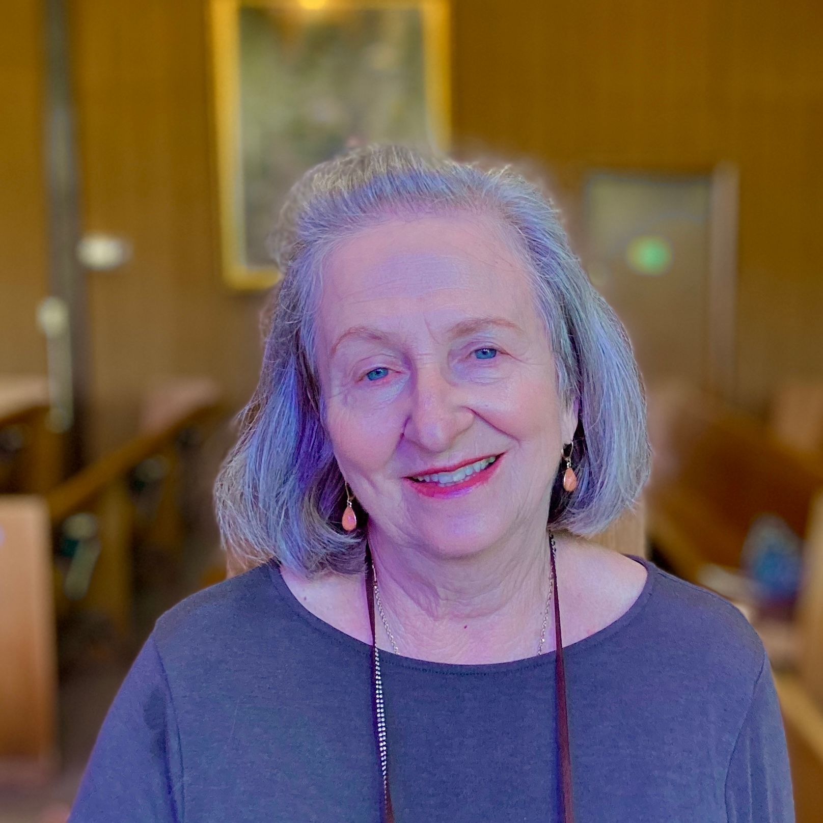 A woman with gray hair and earrings smiles for the camera