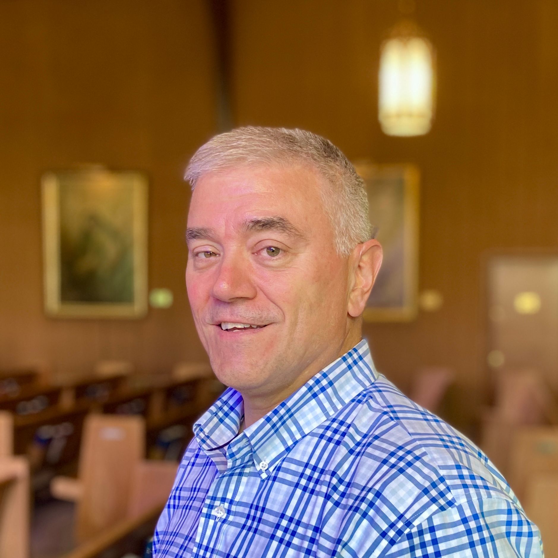 A man in a plaid shirt is smiling in a church