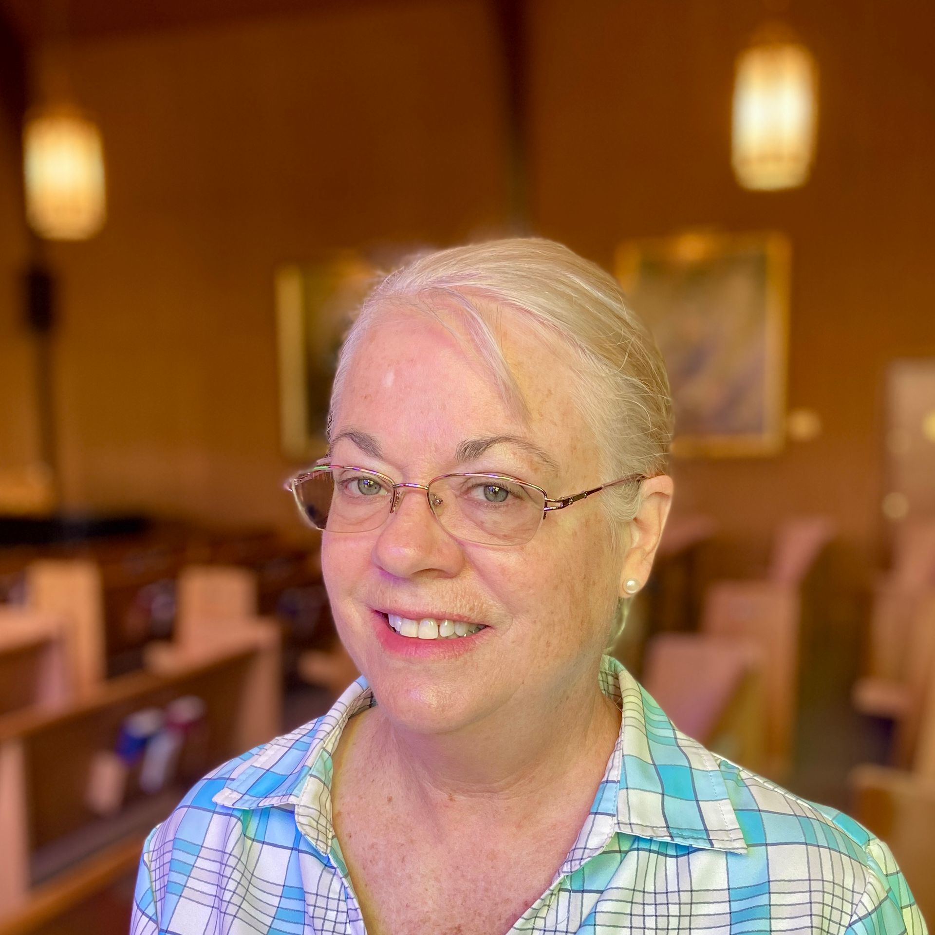 A woman wearing glasses and a blue shirt smiles for the camera