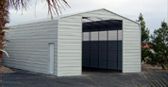 A white garage with a black door is sitting next to a palm tree.