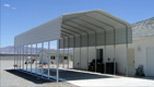 A large white building with a canopy over a parking lot.