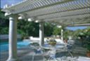 A pergola over a patio with tables and chairs next to a pool.