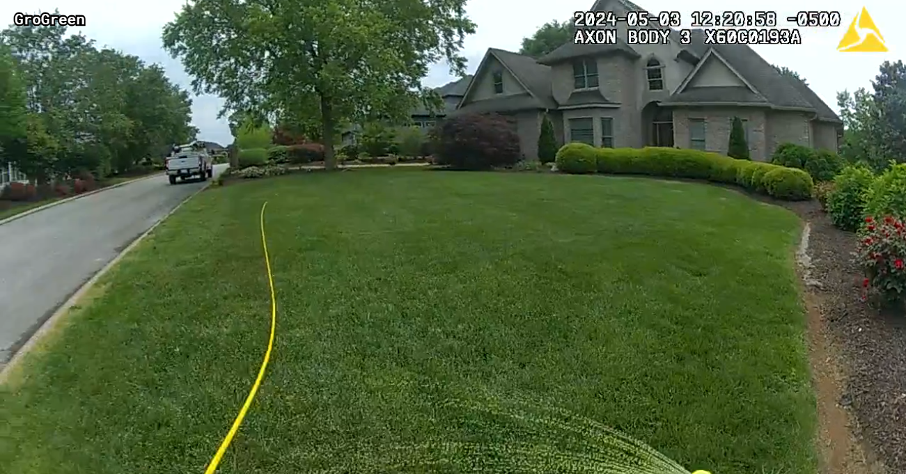 A hose is laying on the grass in front of a house.