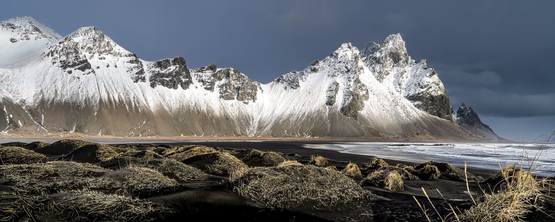 Snow mountains Iceland ice on black beach