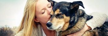 blonde woman kissing pet dog