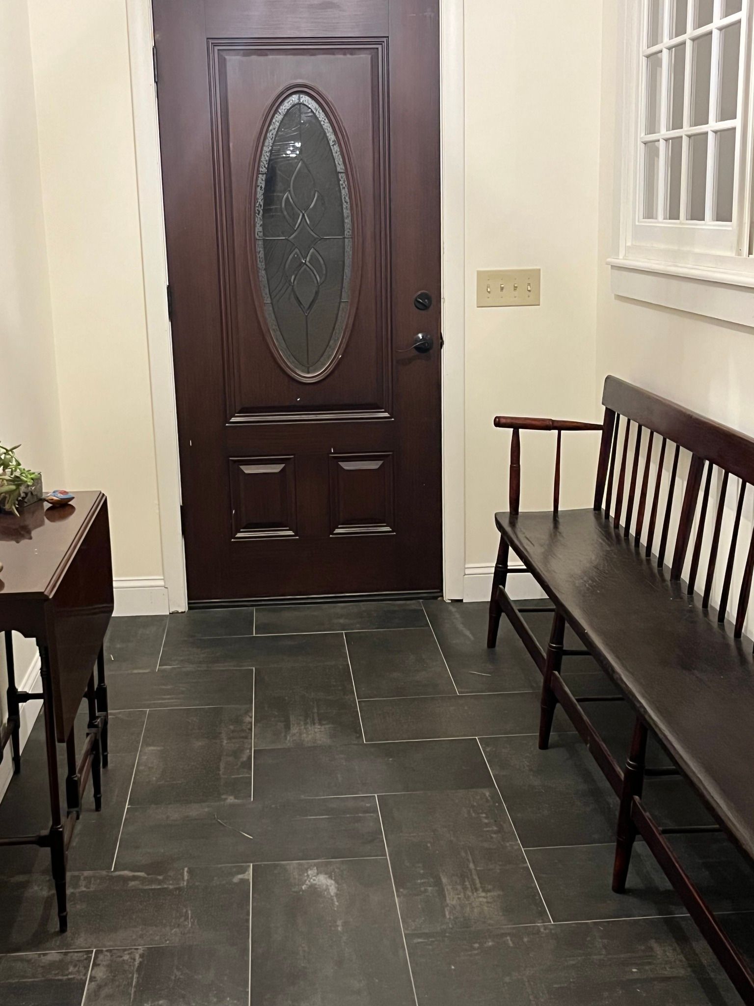 A hallway with a bench and a table in front of a door.