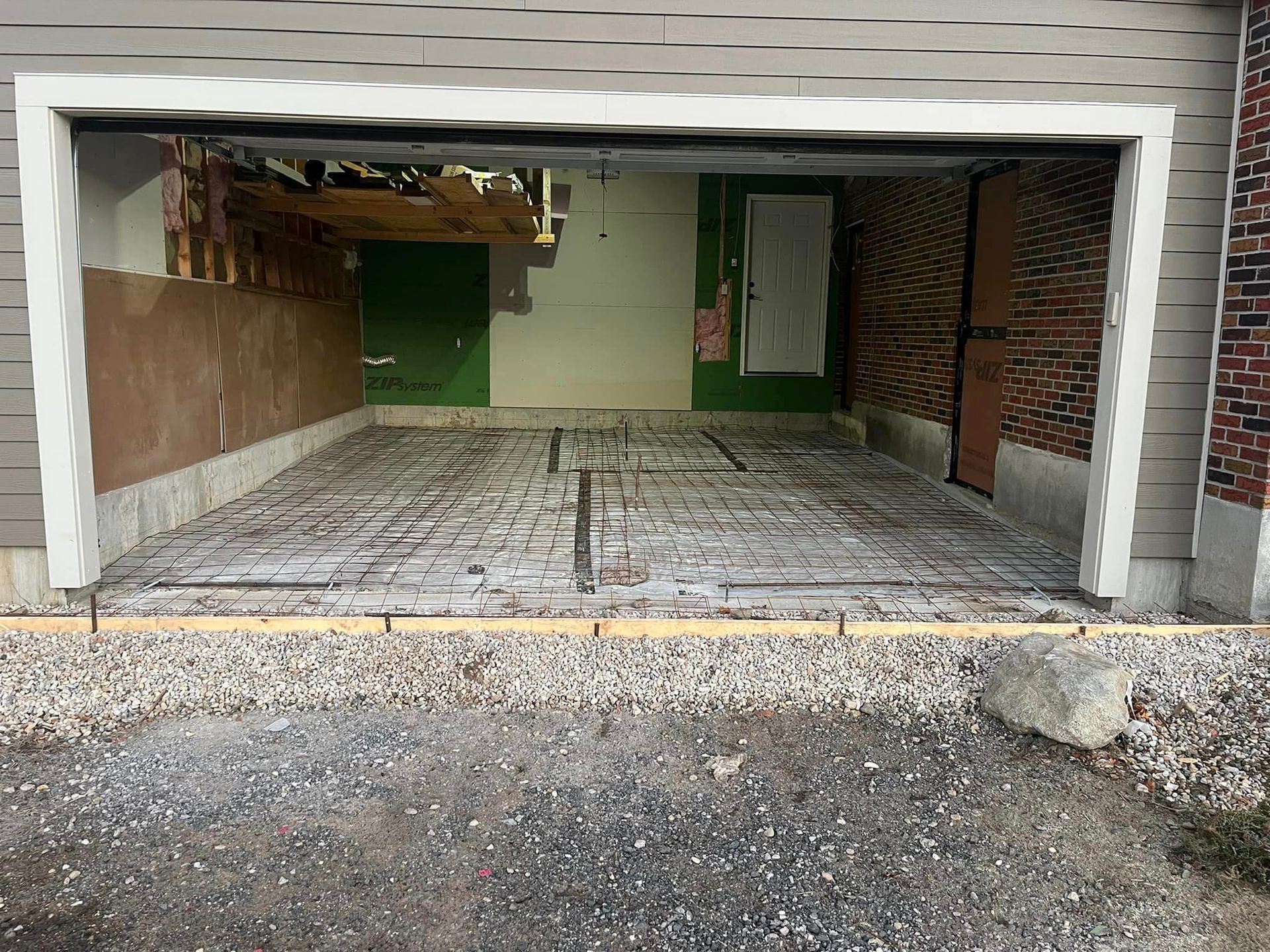 A garage under construction with a concrete floor and a brick wall.