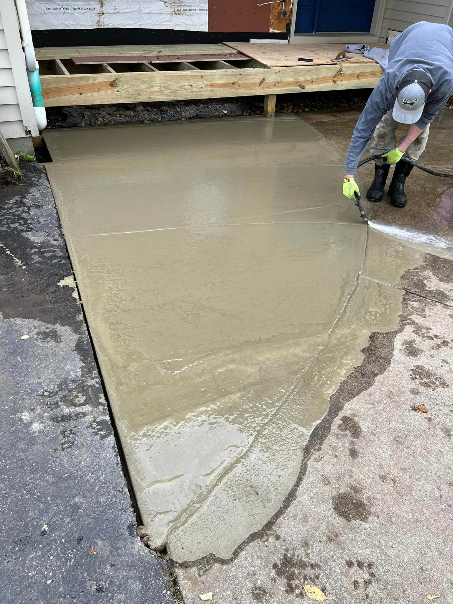 A man is pouring concrete into a driveway.