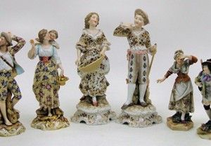 Ceramic figurines in floral dresses and hats. Men and women in various poses, on decorative bases.