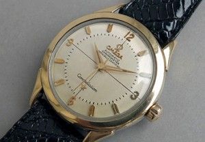 Gold Omega Constellation wristwatch with a black leather band.
