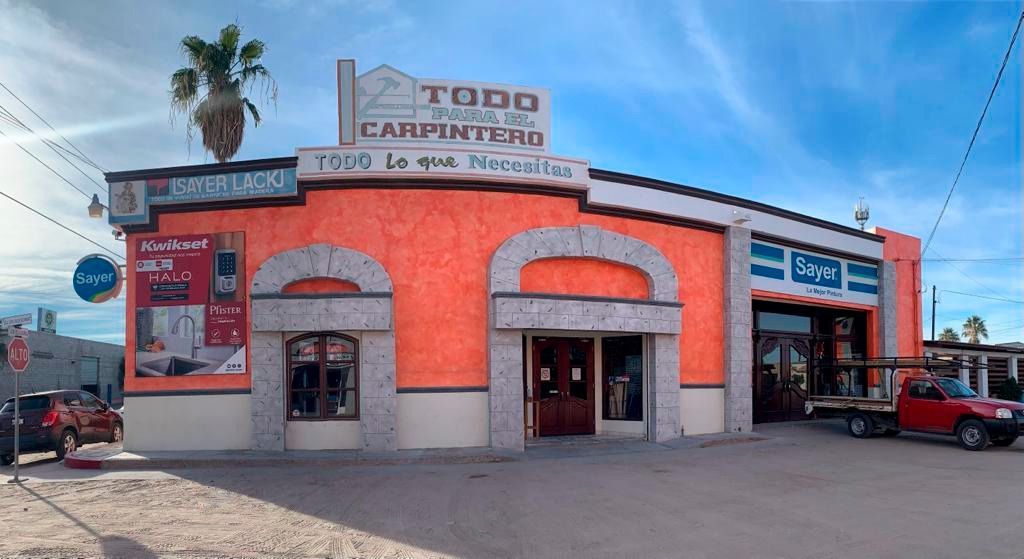 Edificio rosa con letrero de la Línea Plateada, entrada arqueada, coches aparcados y arte en lo alto.