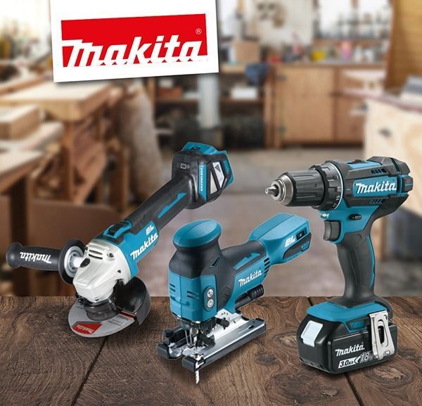 Herramientas eléctricas Makita: amoladora angular, sierra de calar, taladro sobre una superficie de madera, fondo de taller.