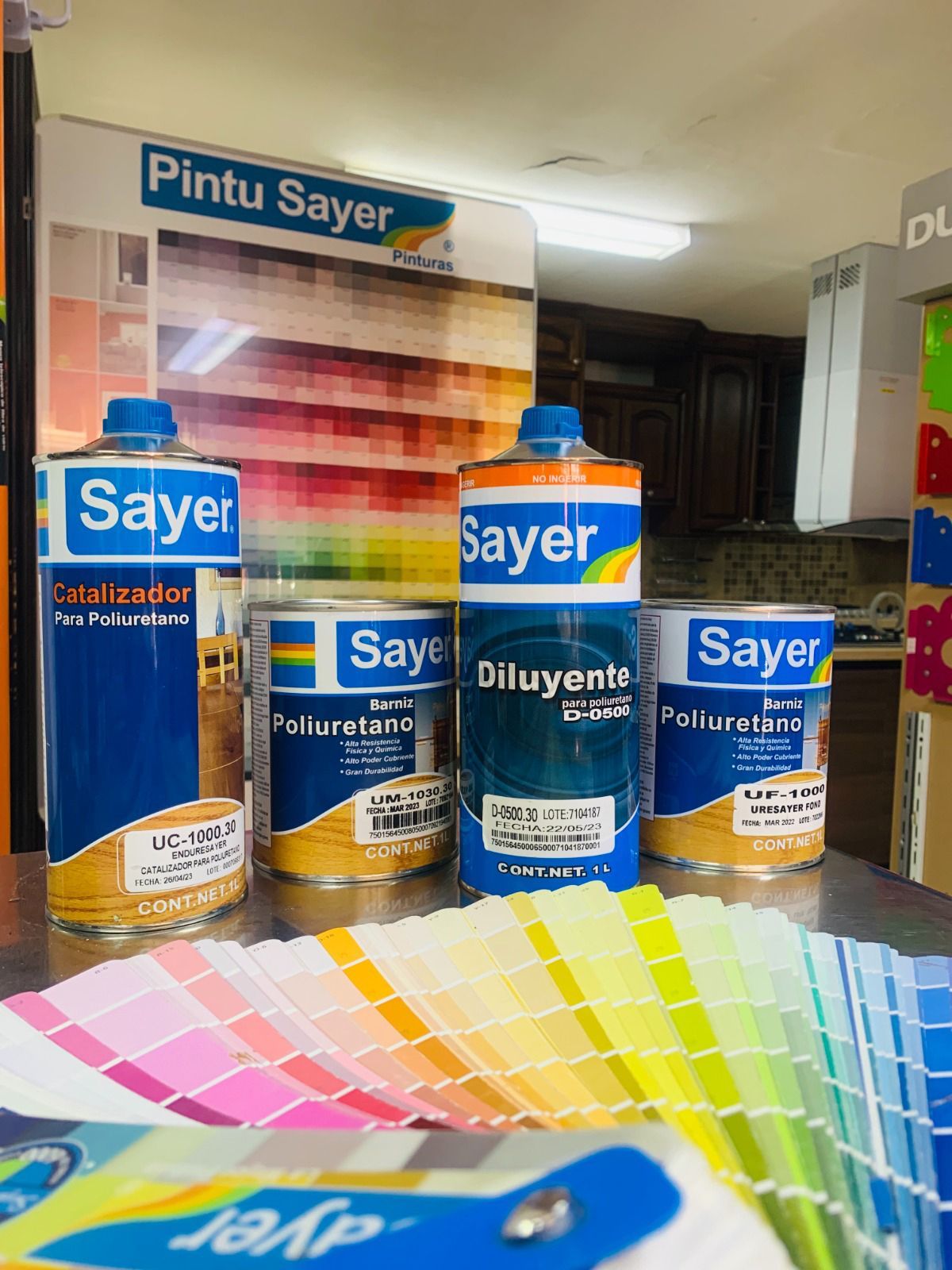 Latas de pintura y muestras de color en exhibición para los productos de Pintu Sayer.