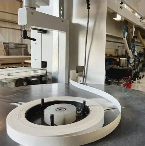 Bobina de cinta de cantear blanca en una máquina en un taller.