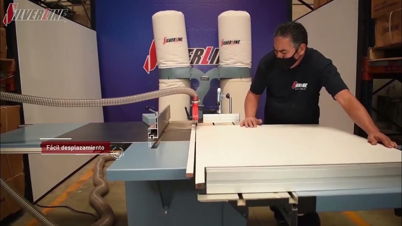 Hombre operando una sierra de carpintería, con mascarilla. Material blanco sobre la mesa de la sierra. Entorno de taller.