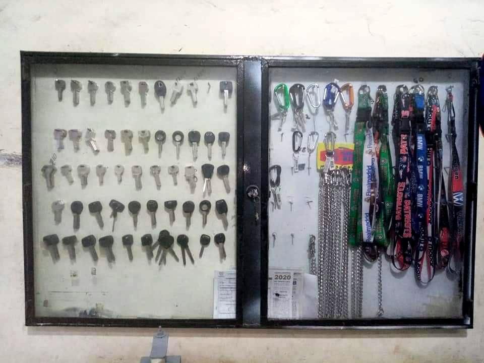 Armario de llaves con filas de llaves y cordones colgados dentro de un marco oscuro en una pared.