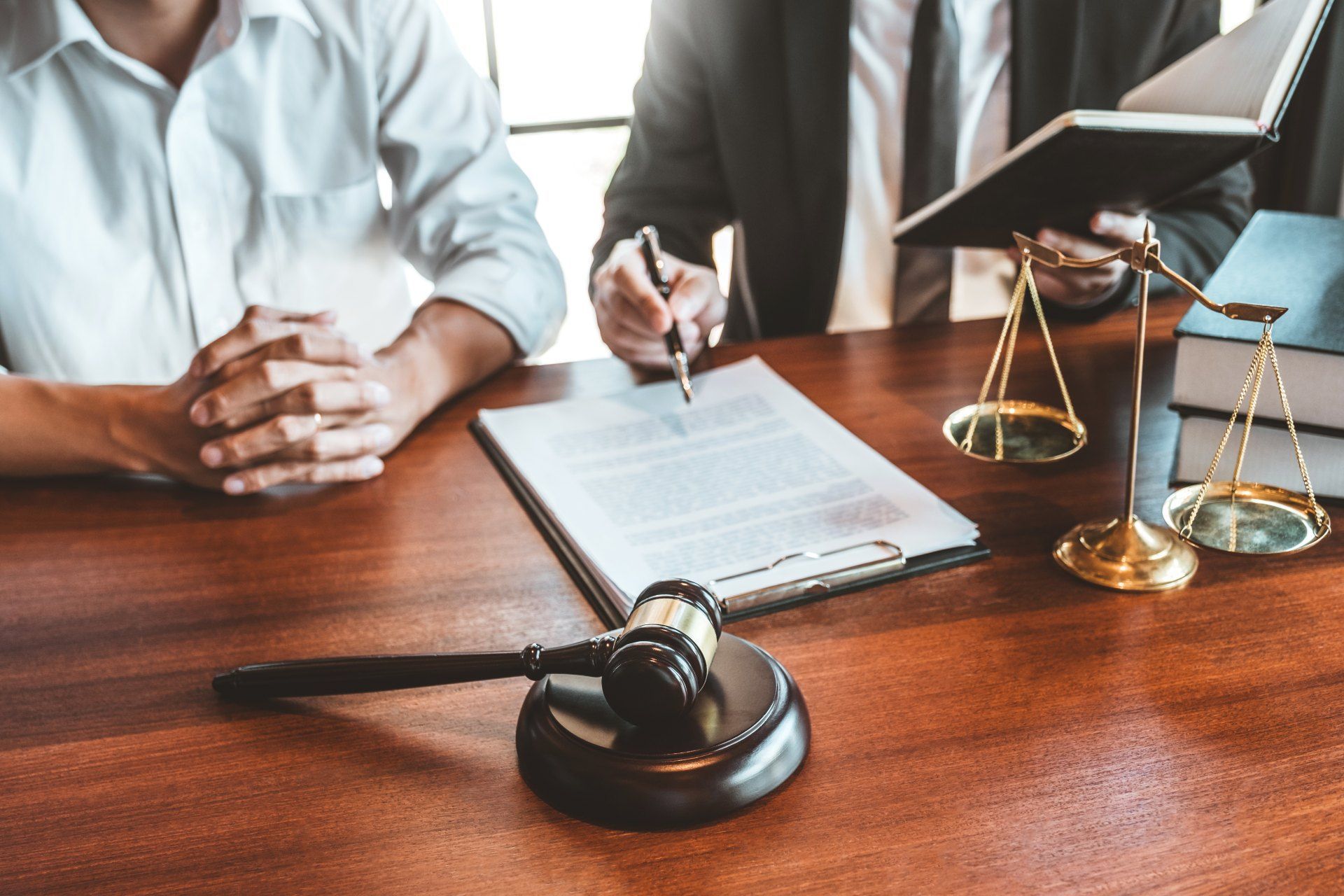 Two men are sitting at a table with a judge 's gavel and scales of justice.