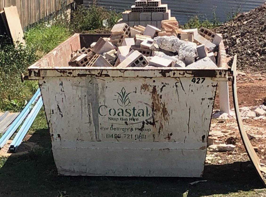A dumpster filled with construction debris, including bricks and concrete, outdoors. — Coastal Skip Bin Hire In Craignish, QLD