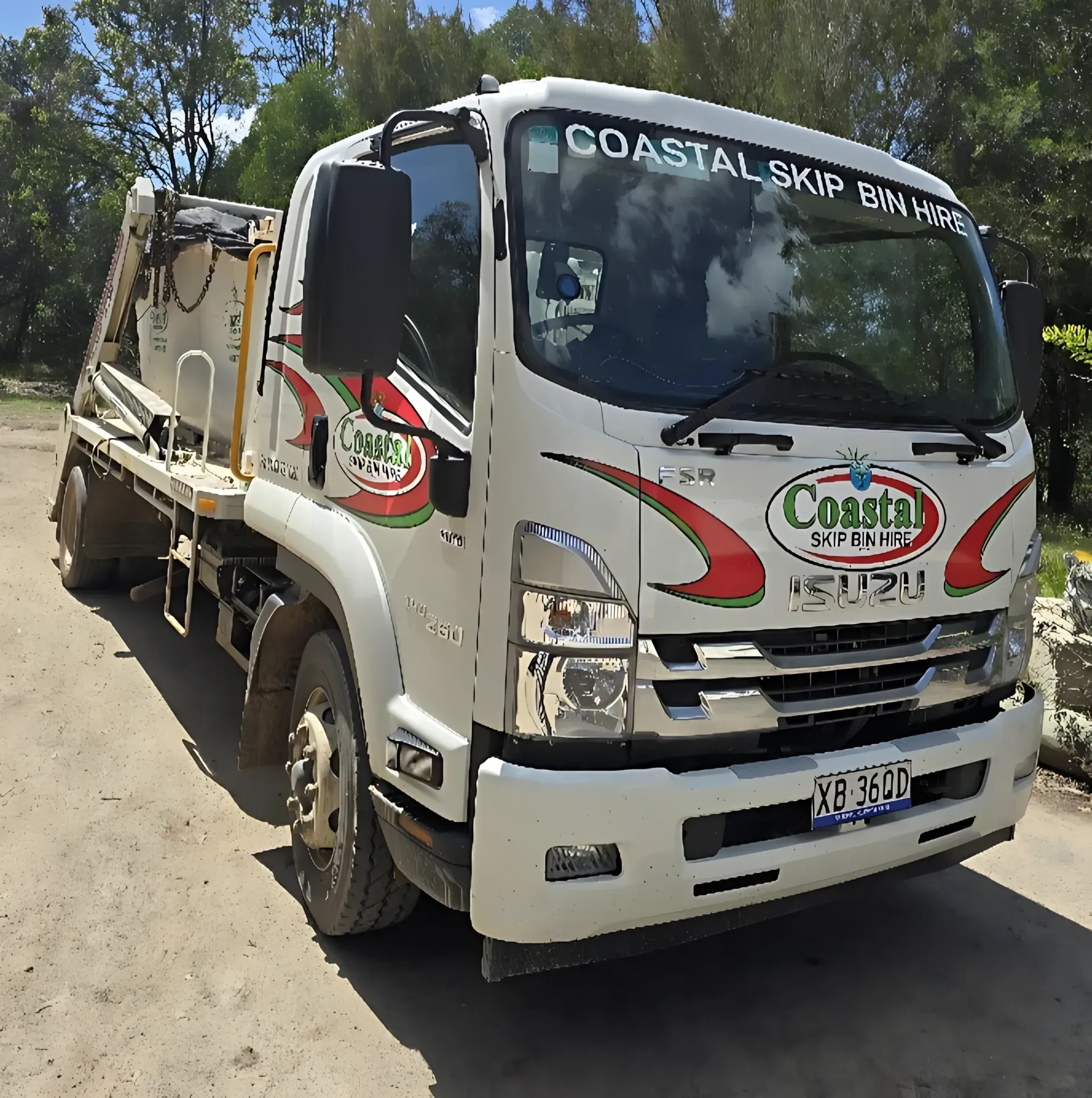 White Coastal Skip Isuzu truck on a gravel road, with logo visible — Coastal Skip Bin Hire In Craignish, QLD