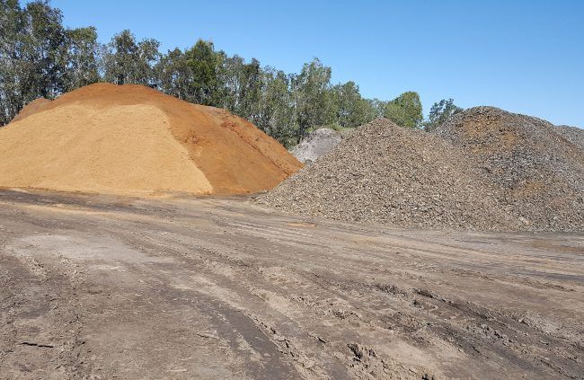 Piles of Tan Sand, Gray Gravel, and Dirt Under a Blue Sky — Coastal Skip Bin Hire In Craignish, QLD