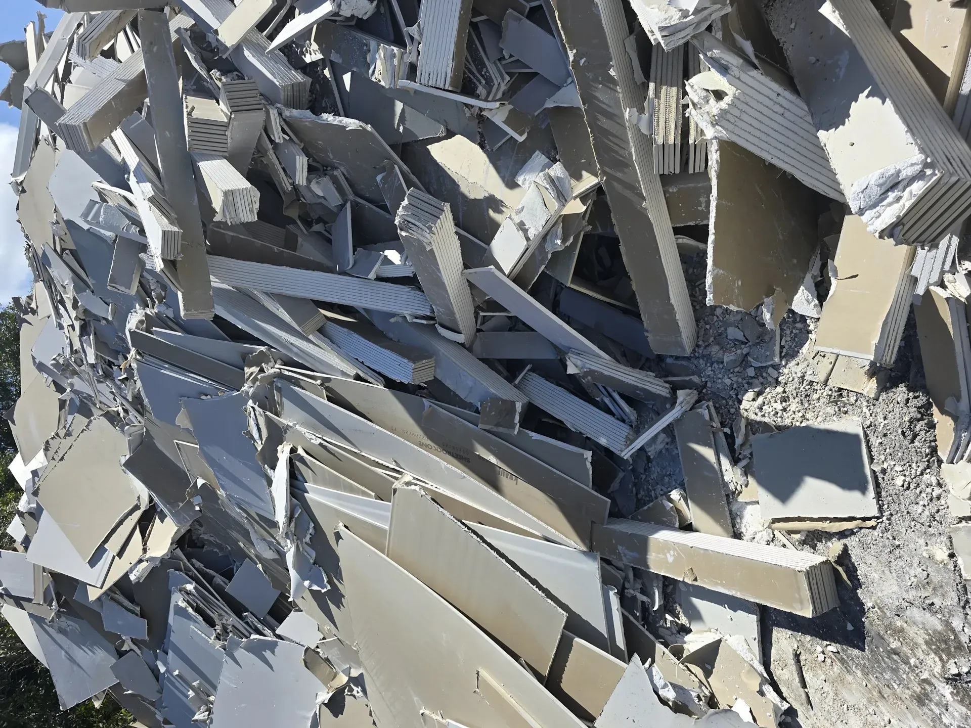 Pile of light gray construction debris, possibly siding or drywall, outdoors. — Coastal Skip Bin Hire In Craignish, QLD