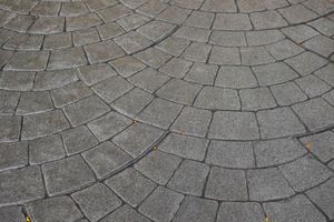 A close up of a circular pattern of bricks on a sidewalk.