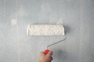 A person is painting a wall with a paint roller.