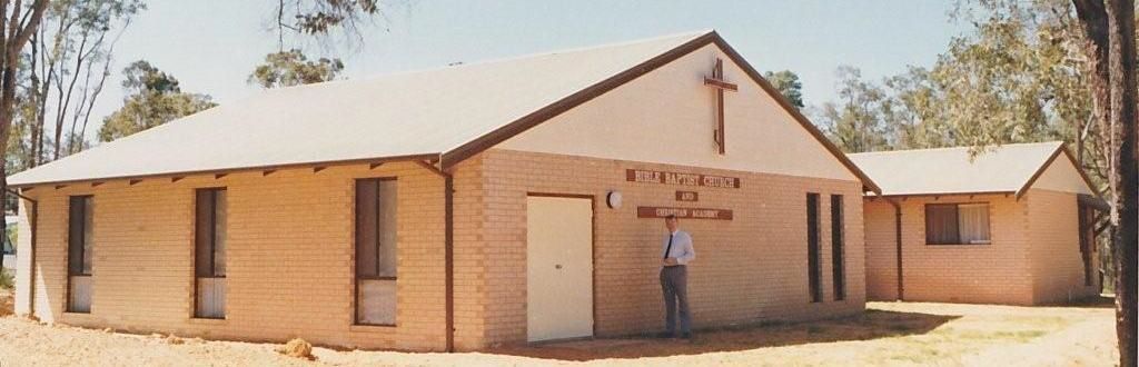 A man stands in front of a church with a cross on it