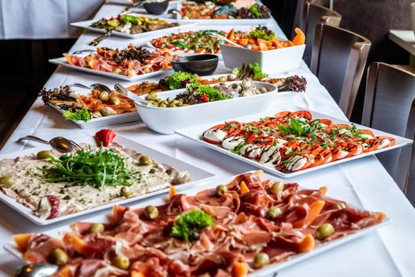 Buffet table with assorted fresh salads and appetizers on white platters in a restaurant
