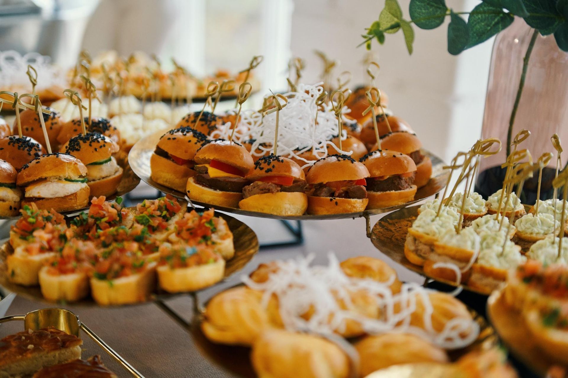 Assorted mini sandwiches, tarts, and pastries arranged on tiered trays at a buffet table