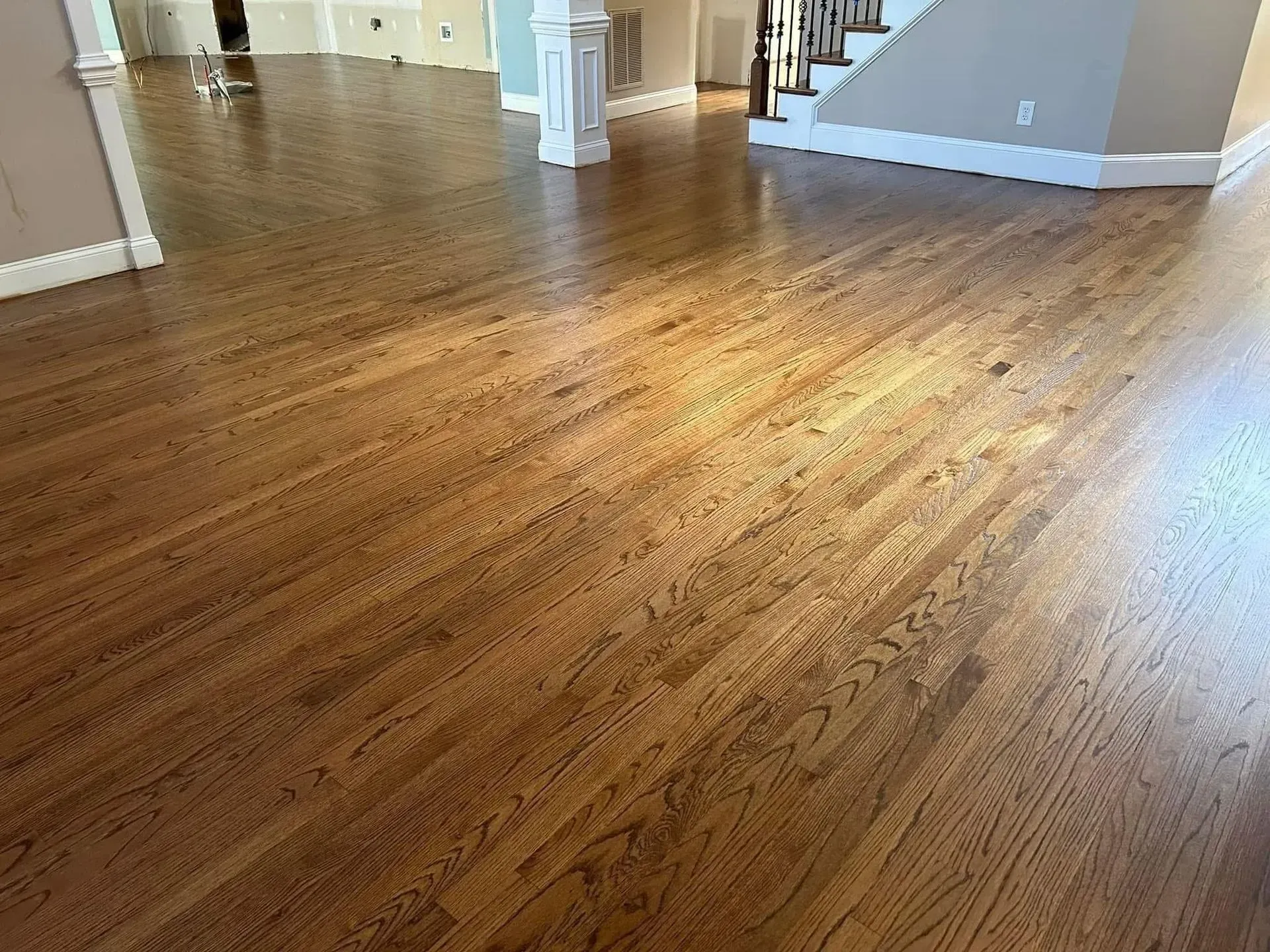 Empty hardwood floor in a bright, unfurnished room with white columns and gray walls