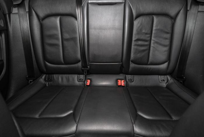 A close up of the back seat of a car with seat belts.