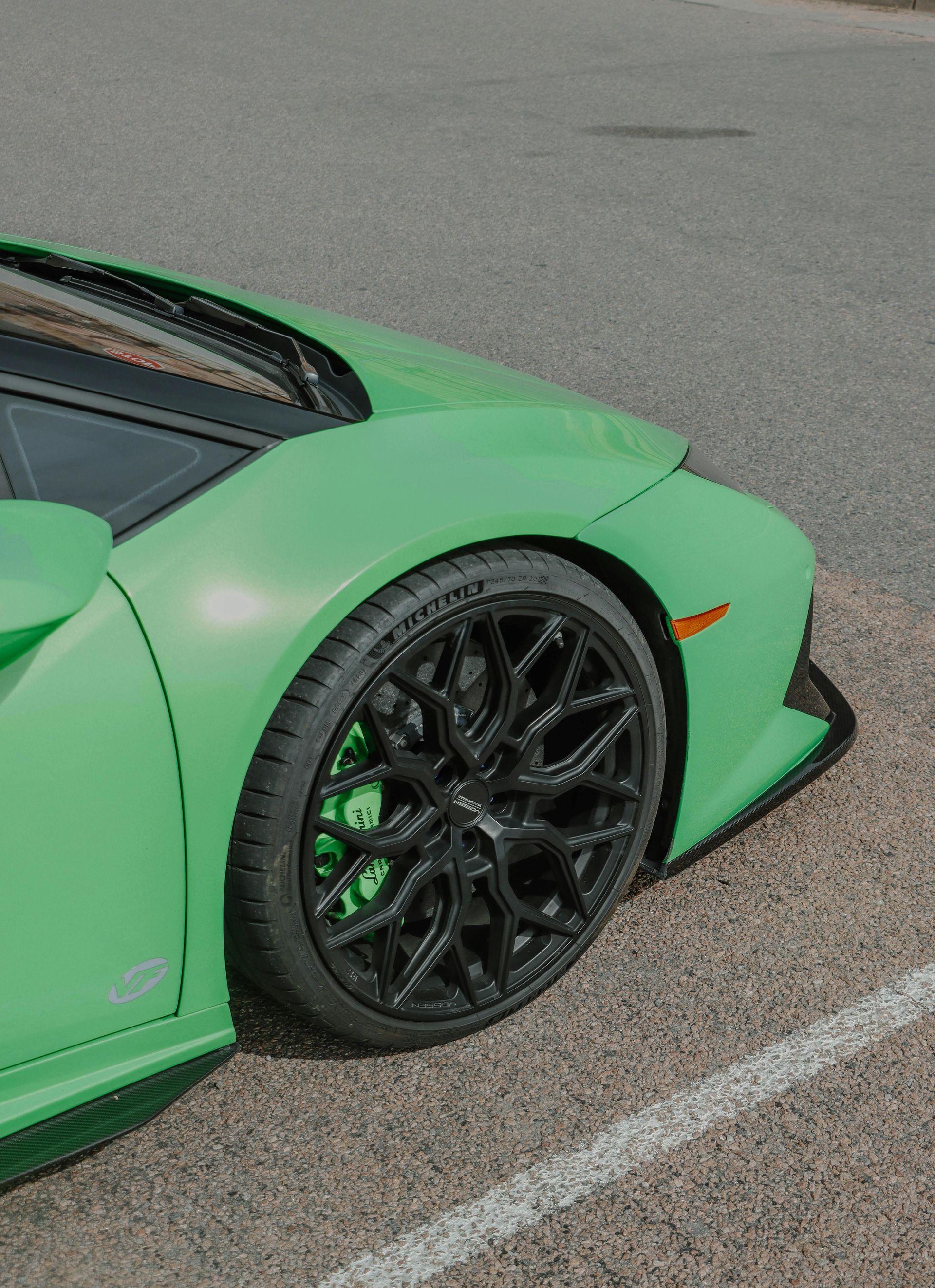 A green sports car is parked in a parking lot.