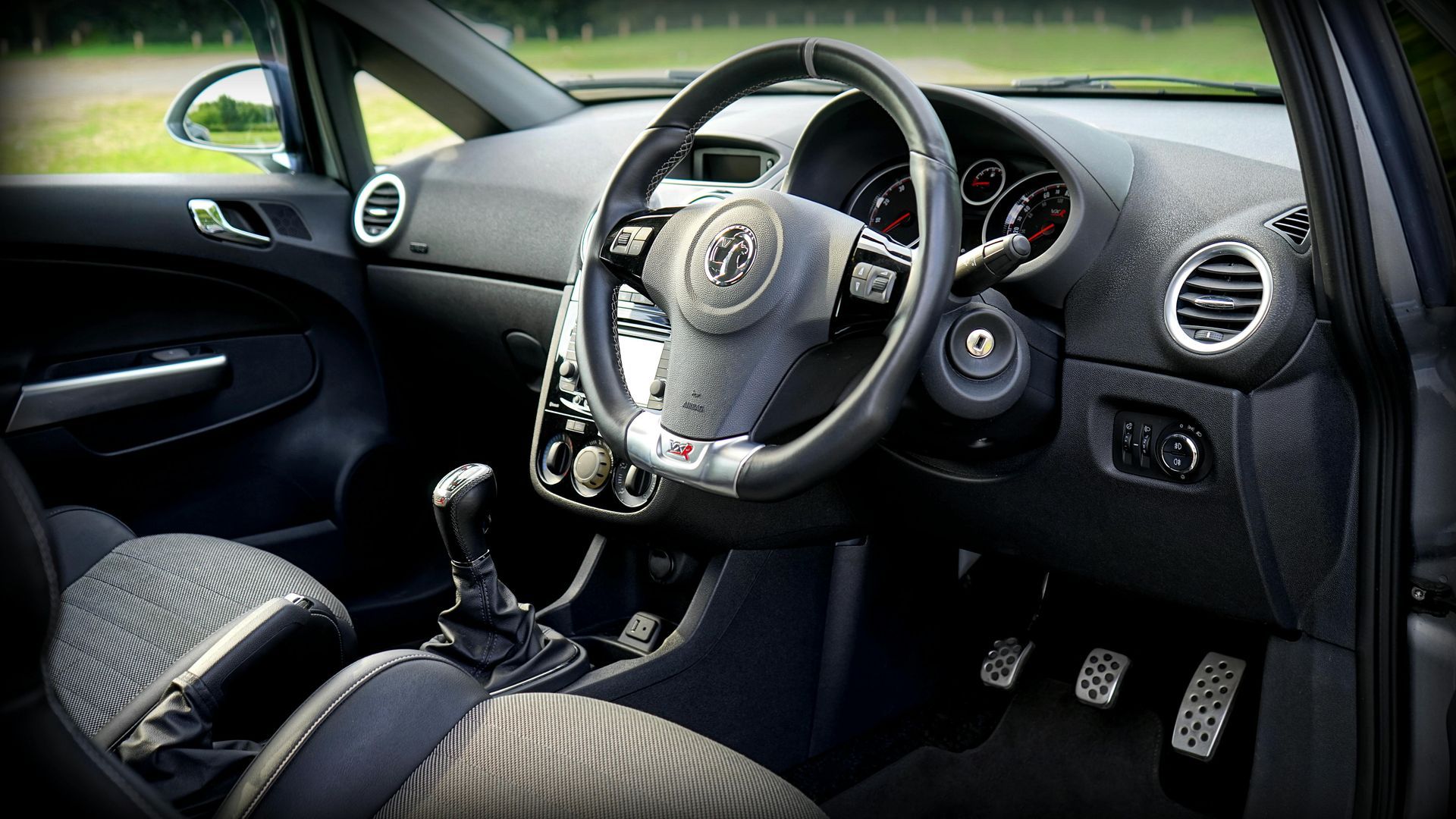 The interior of a car with a steering wheel and pedals